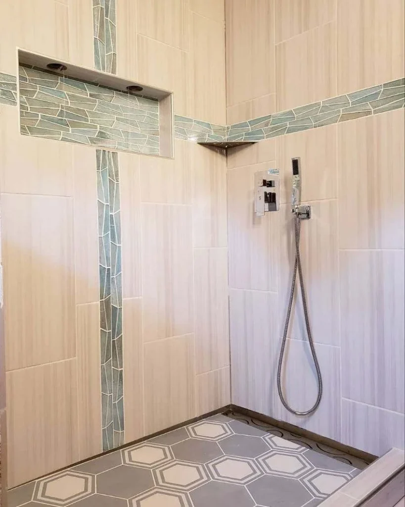 Shower with vertical wall tile, mosaic accent and a patterned floor