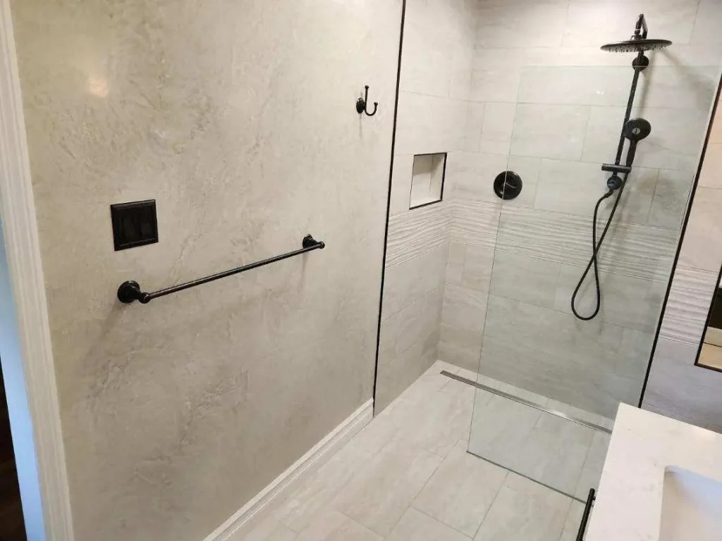 Walk-in shower with light wall tile, glass enclosure and black fixtures