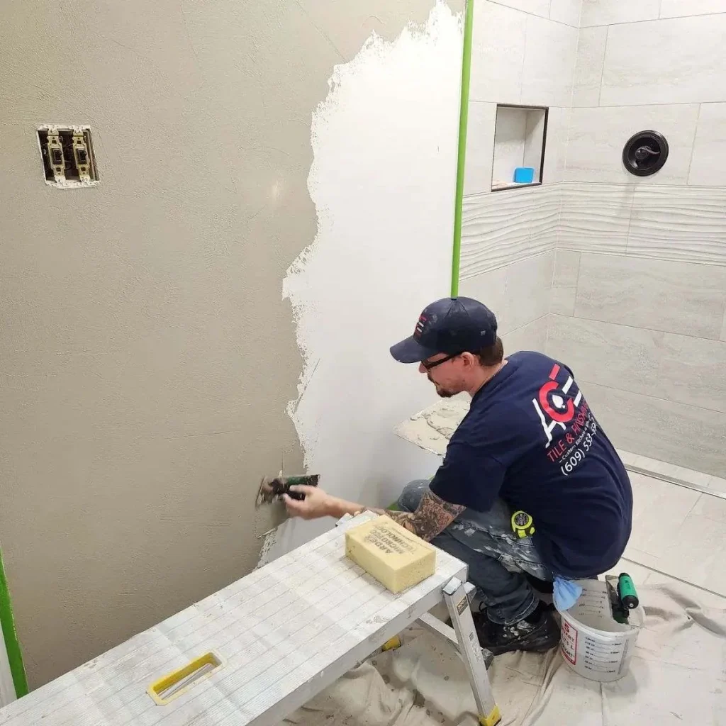 Ace Tile and Plaster contractor applying a wall finish beside a tiled shower
